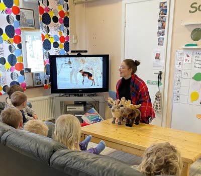Berättarstund med små barn som tittar på bild på renar.