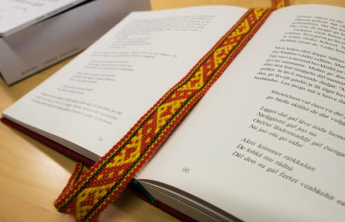 An open book with a colourful woven bookmark.