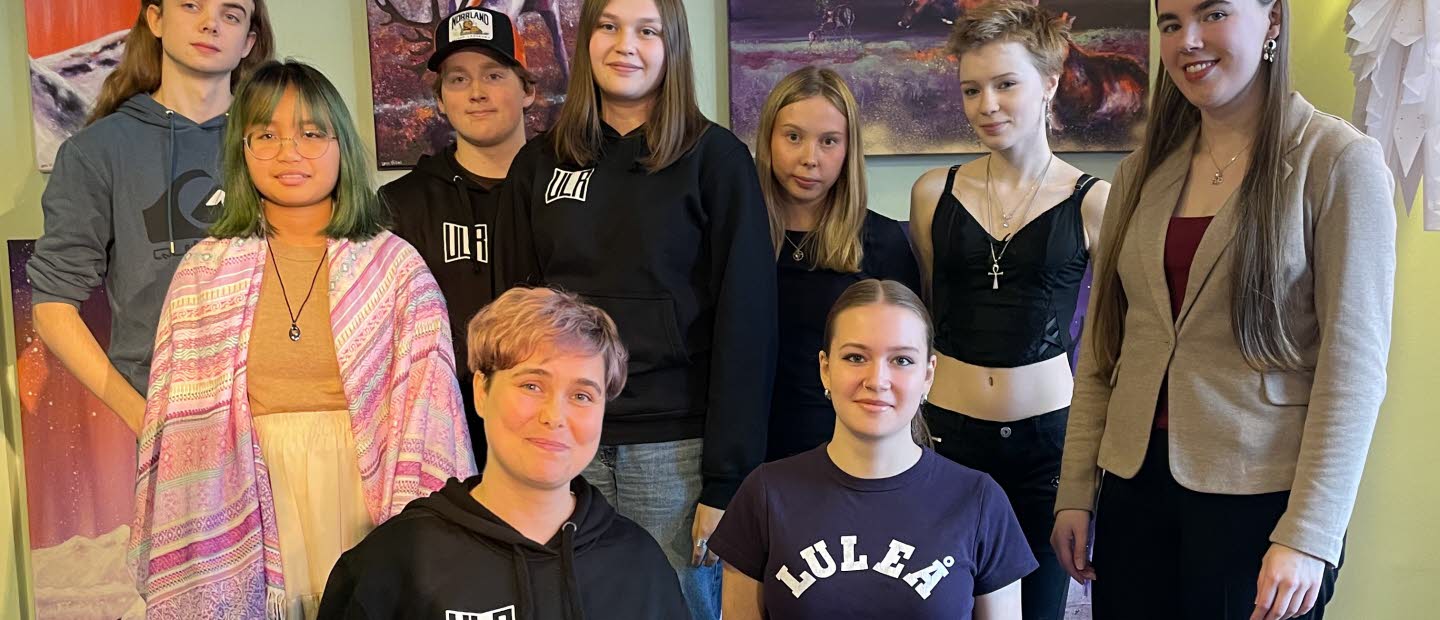 Två personer sitter på knä och sju personer står runt omkring dem.