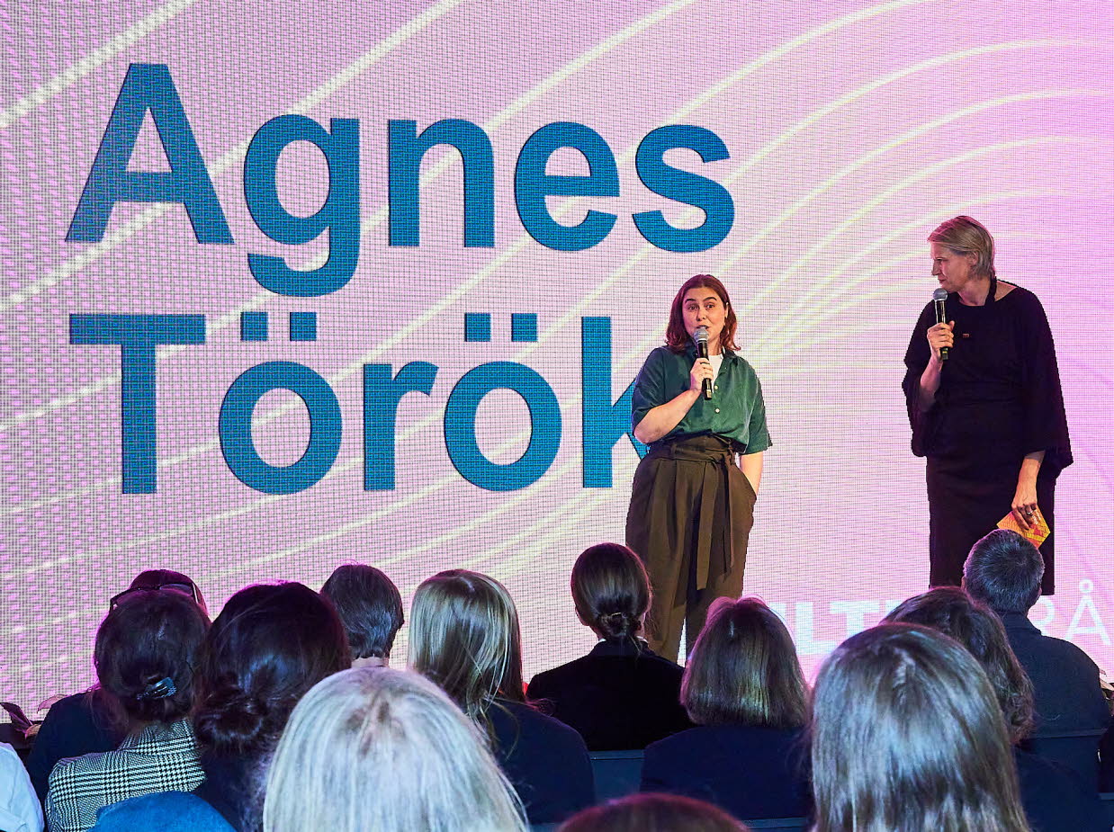 Två personer samtalar på en scen.