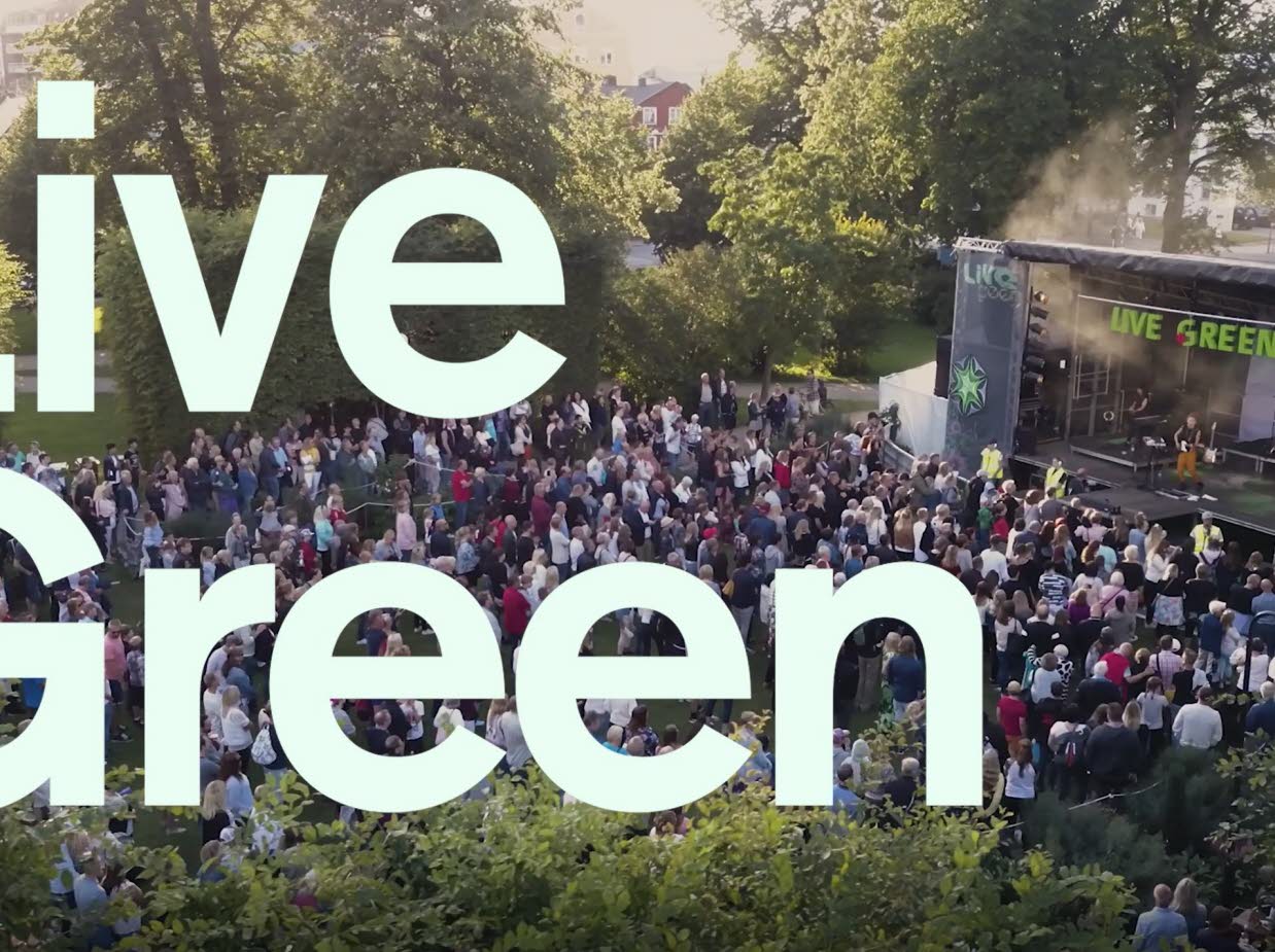 Text med LiveGreen, i bakgrunden en utomhusscen med publik.