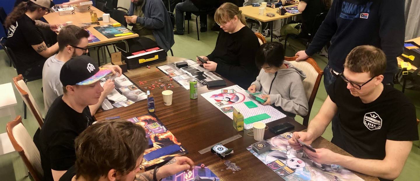 Unga sitter runt ett bord och spelaar brädspel.