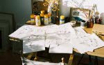 Ett soldränkt skrivbord täckt av papper med skisser på Astrid Lindgren
