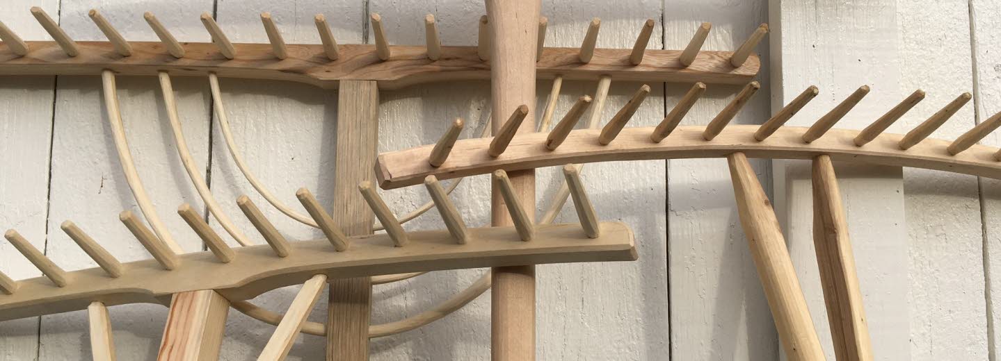 Fyra handtillverkade träräfsor mot en vägg.