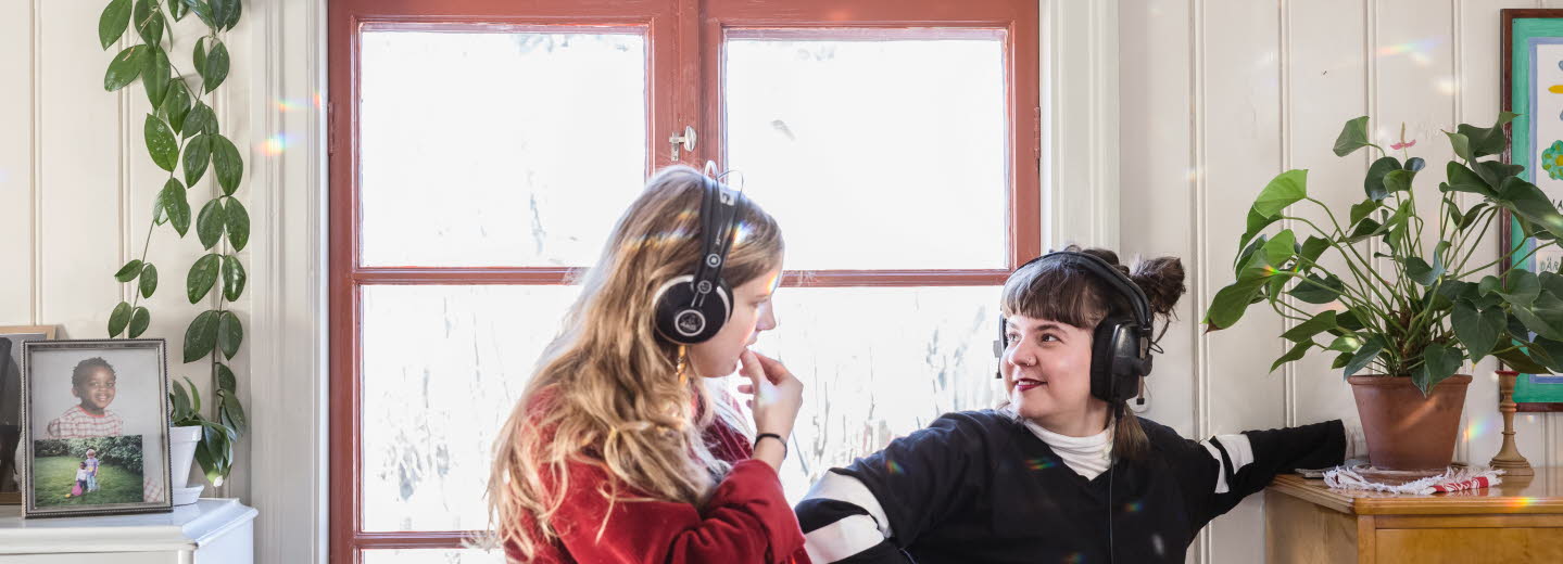  Två unga kvinnor med hörlurar som tittar på varandra.