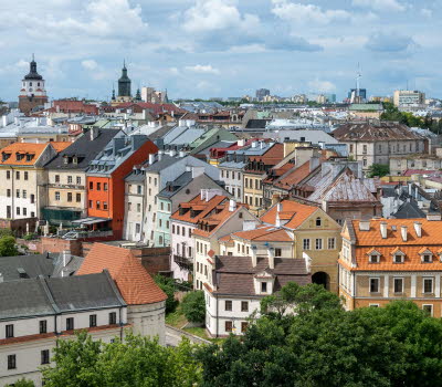 Bild över flera hustak i staden Lublin. I bakgrunden skymtas ett kyrktorn. Vädret är sol med växlande molnighet.