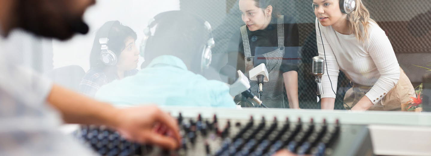 Radioinspelning. Man vid mixerbord och tre tjejer och en man samtalar med mikrofoner och headsets.