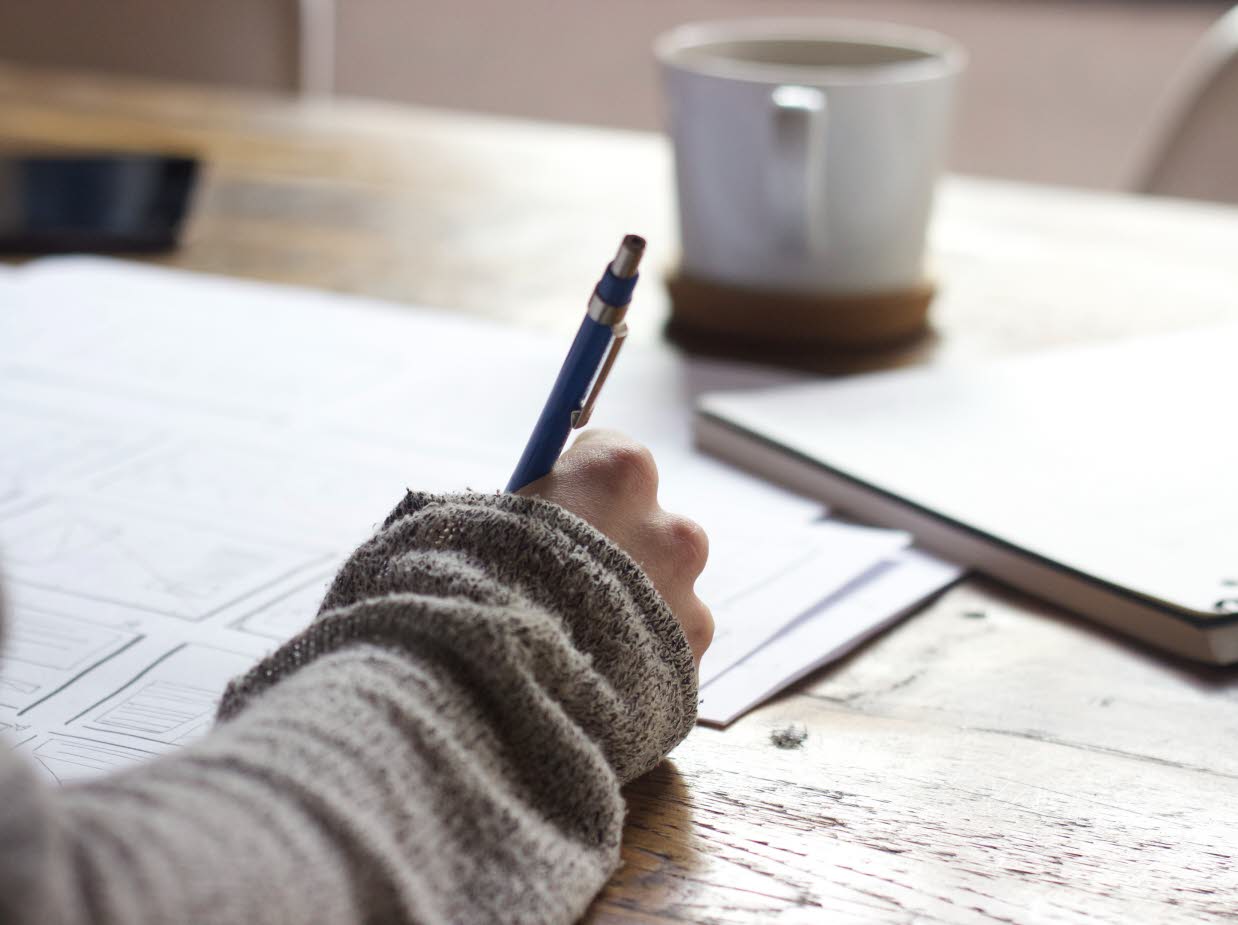 Närbild på en hand som fyller i uppgifter på ett papper. 