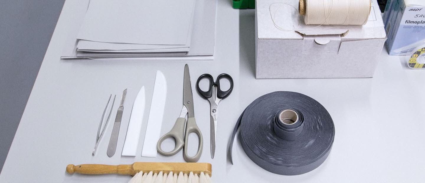 Bord med olika föremål som sax, tejp, borste, anteckningsblock.
