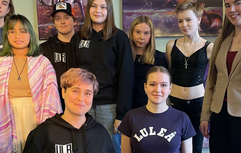 Två personer sitter på knä och sju personer står runt omkring dem.