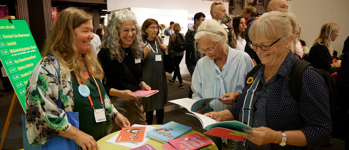 Människor läser i broschyrer i Kulturrådets monter på Bokmässan. 
