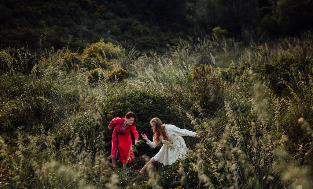 The dancer Liv Aira and jojk artist Elin Teilus performing in a field.