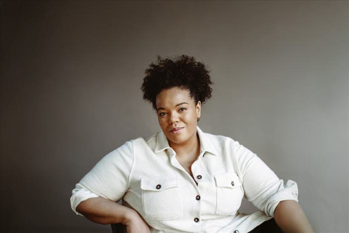 Maria Fröhlich is sitting in a relaxed posture, wearing a white shirt.