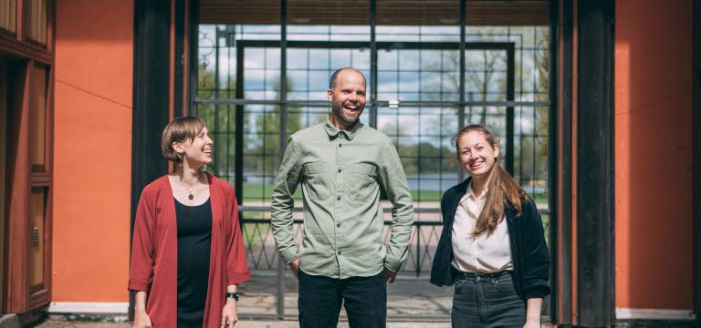 Sara Jane, Olof Göthlin och Tove Klang från Scenbruket står framför byggnaden. Det är sommar och de ser glada ut.