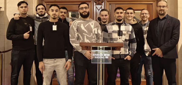 Bild på en grupp mestadels unga män bakom en talarstol som visar att de är i Riksdagen.