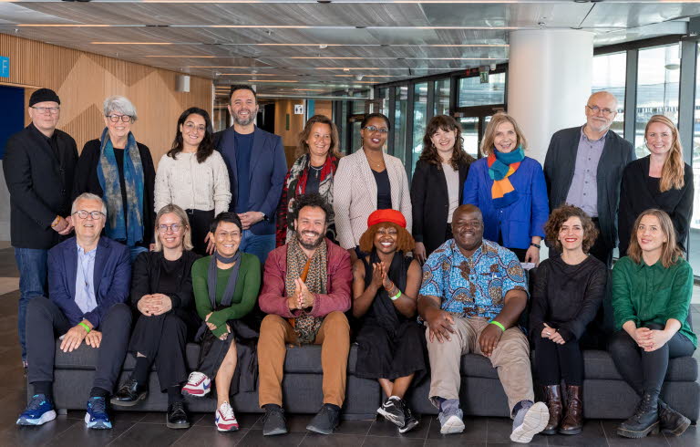 Gruppbild på partners. 18 personer står bakom och sitter i en soffa. De ser alla glada ut och tittar in i kameran.