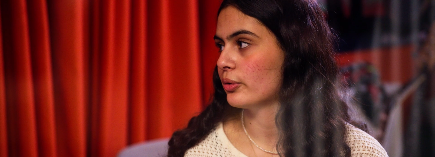 En kvinna som står framför ett draperi.