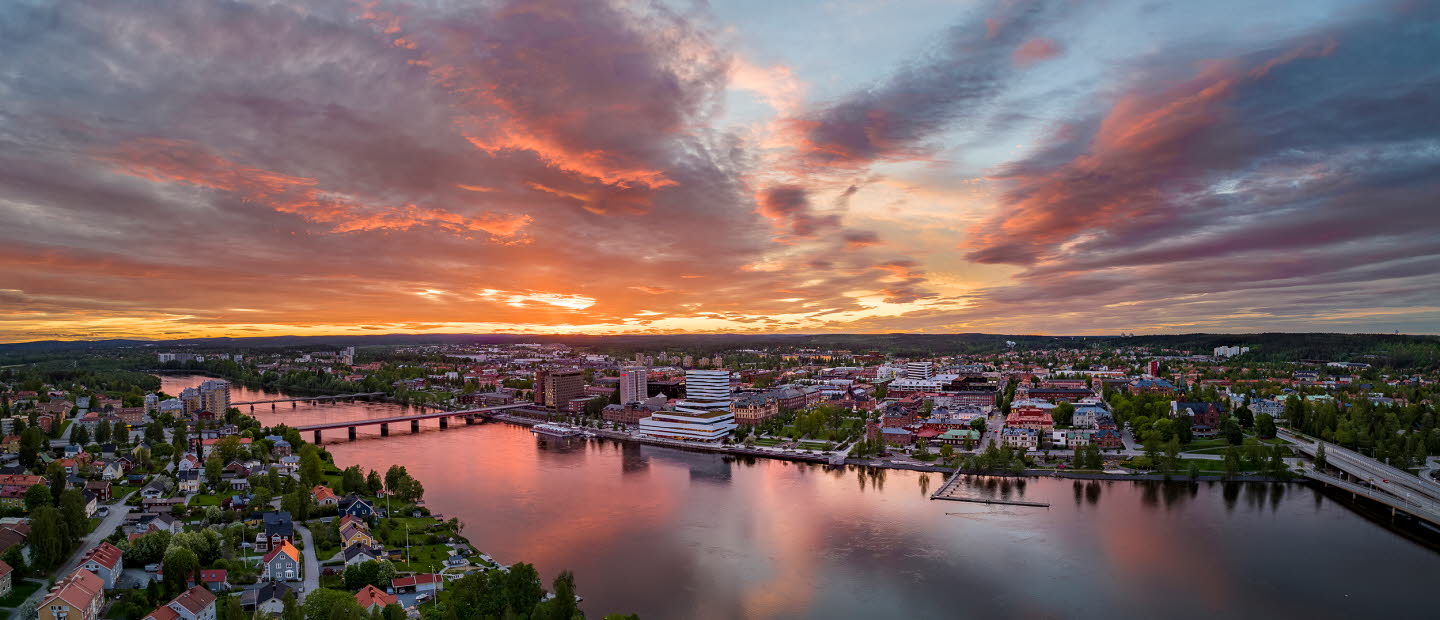 Drönarvy över Umeå och älven i solnedgång.