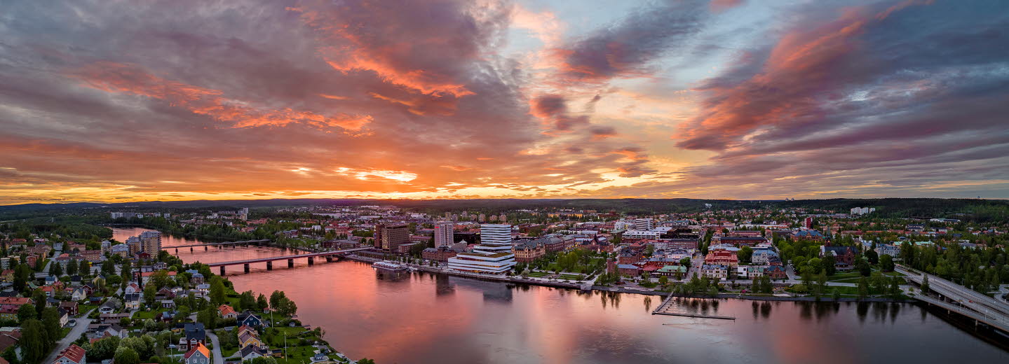 Drönarvy över Umeå och älven i solnedgång.