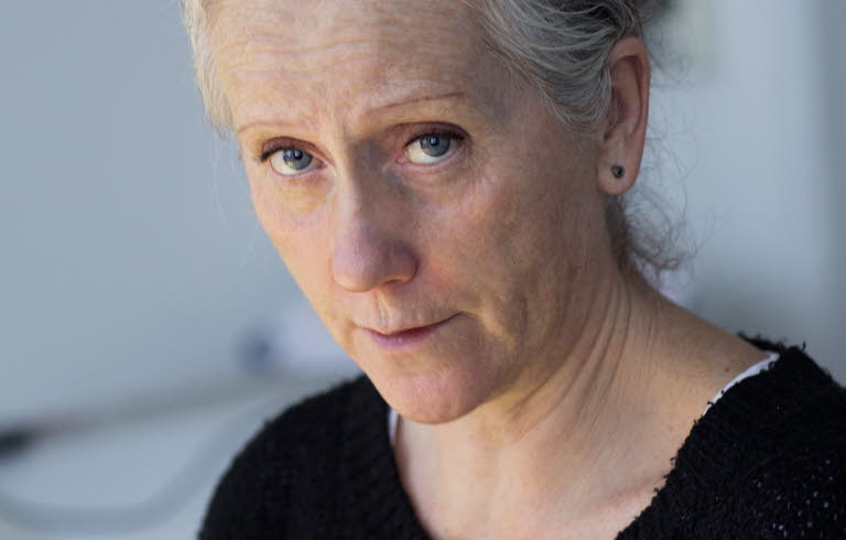 Portrait of Eva Lindström. She's wearing a black sweater and is looking towards the camera, holding a pencil.