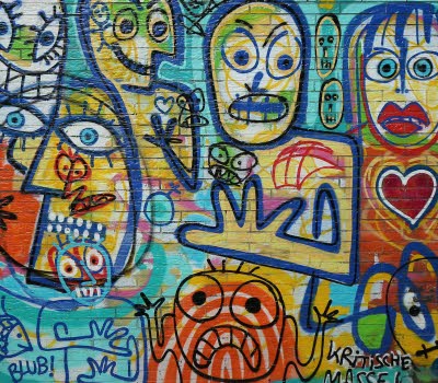 Tegelvägg fylld med grafitti med målade ansikten i glada färger.