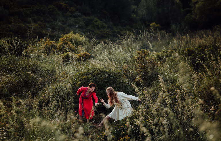 The dancer Liv Aira and jojk artist Elin Teilus performing in a field.