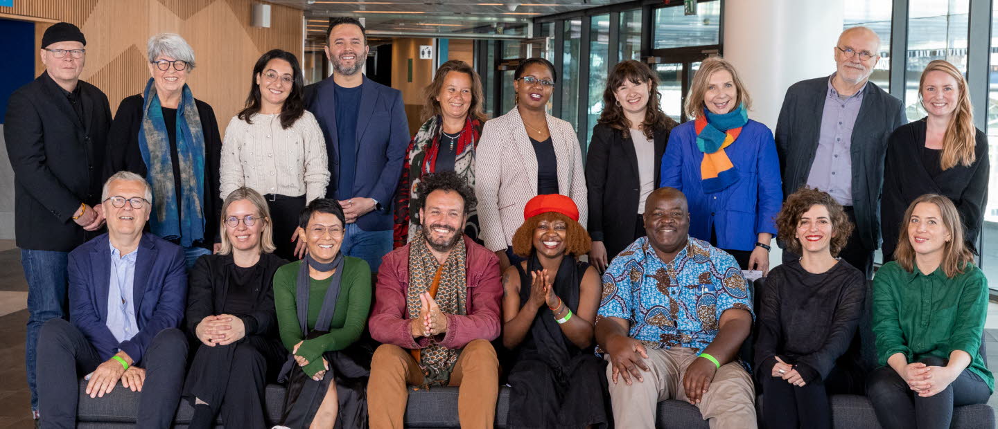 Gruppbild på partners. 18 personer står bakom och sitter i en soffa. De ser alla glada ut och tittar in i kameran.