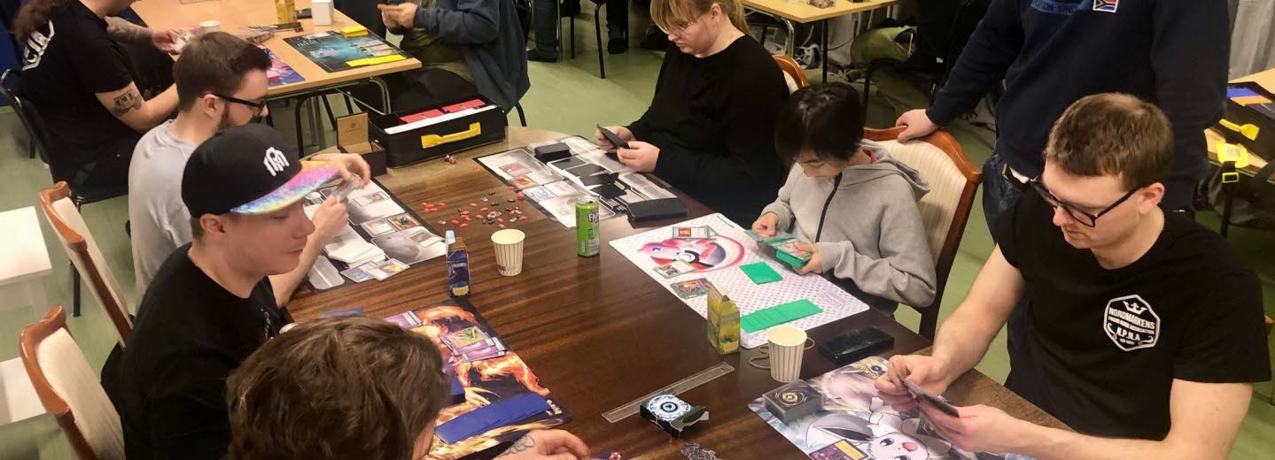 Unga sitter runt ett bord och spelaar brädspel.