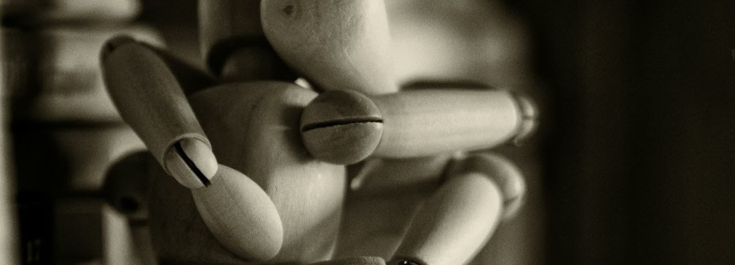 Två människomodeller i trä kramas. 