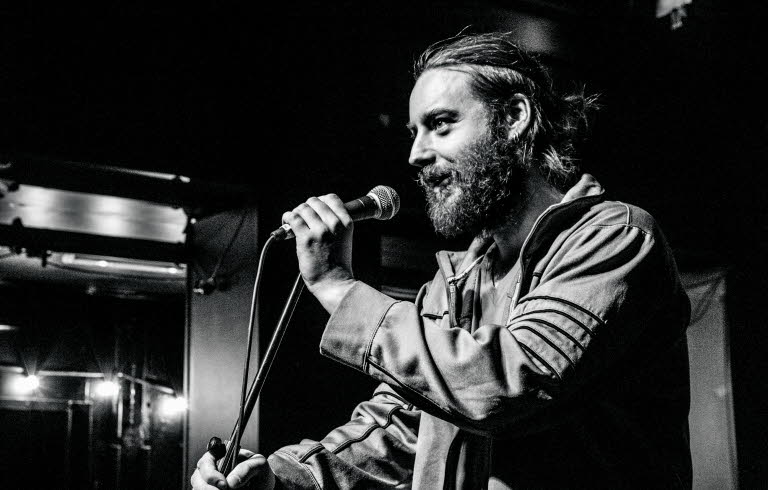 Photo of christian on stage talking into a microphone.