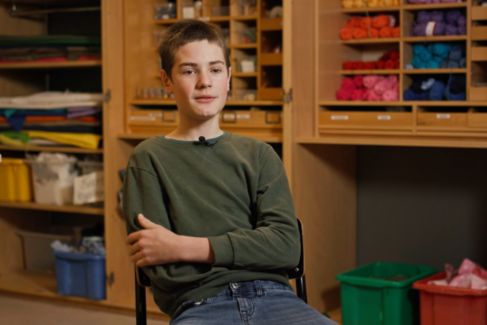 En pojke sitter på en stol i en intervjusituation.