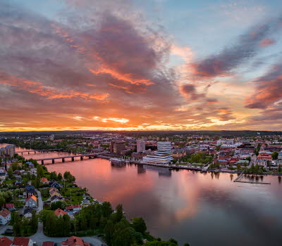 Drönarvy över Umeå och älven i solnedgång.