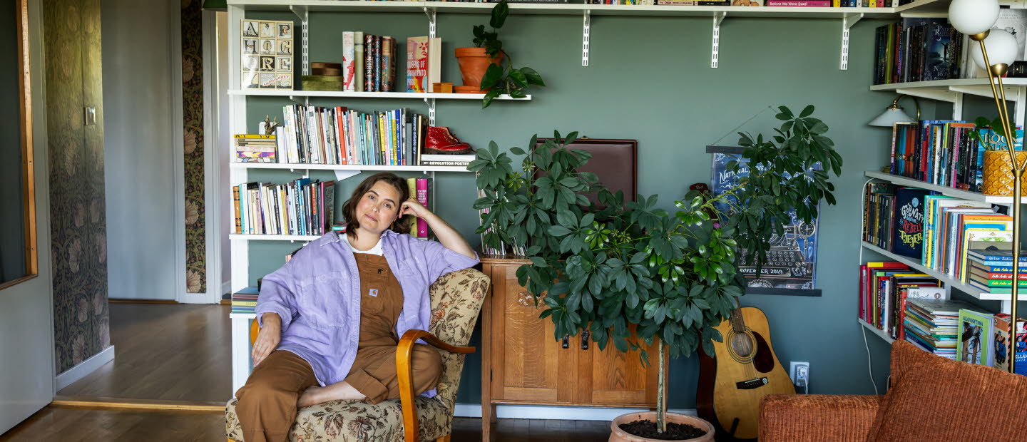 Läsambassadören Agnes Török i en fåtölj framför en bokhylla.