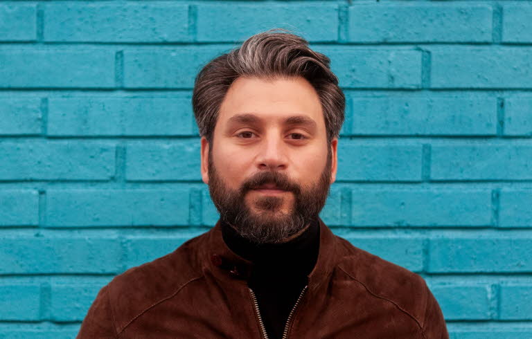 Fotografi av Daniel Boyacioglu mot en blå bakgrund