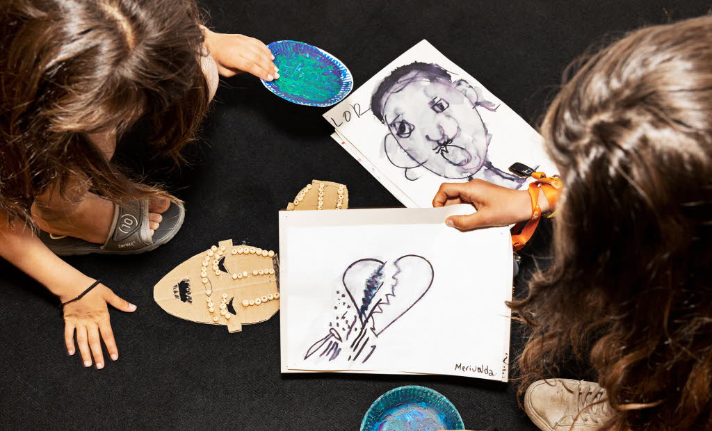 Två personer uppifrån som har teckningar framför sig, med bland annat ett brustet hjärta.