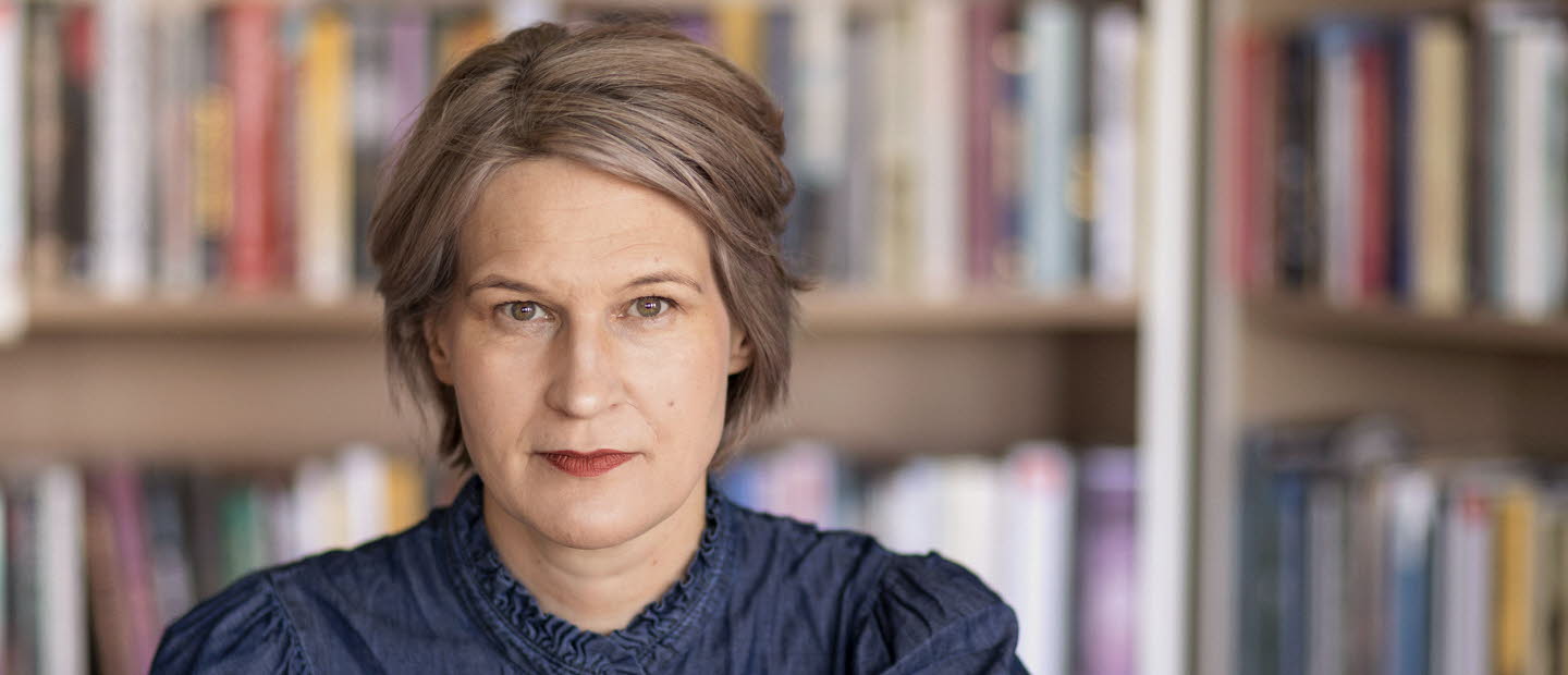 Porträttfotografi av en medelålders kvinna, Kulturrådets generaldirektör. I bakgrunden bokhyllor med böcker.