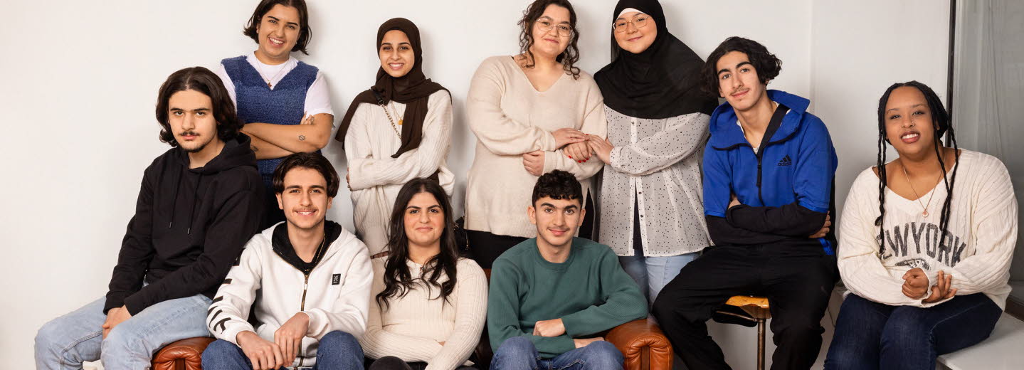 Gruppbild: En kvinna och nio ungdomar - både pojkar och flickor. Gruppen har trängt ihop sig i ena hörnet av ett rum och är samlade kring en soffa.