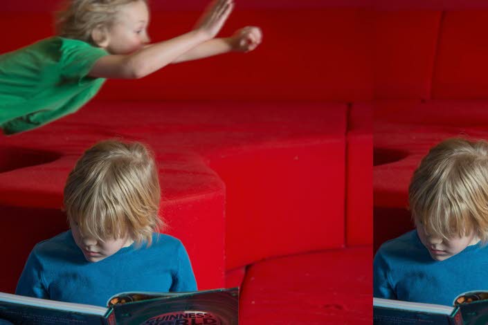 Ett läsande och ett flygande barn i bakgrunden