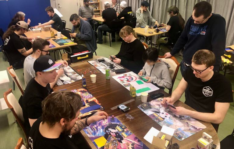 Unga sitter runt ett bord och spelaar brädspel.