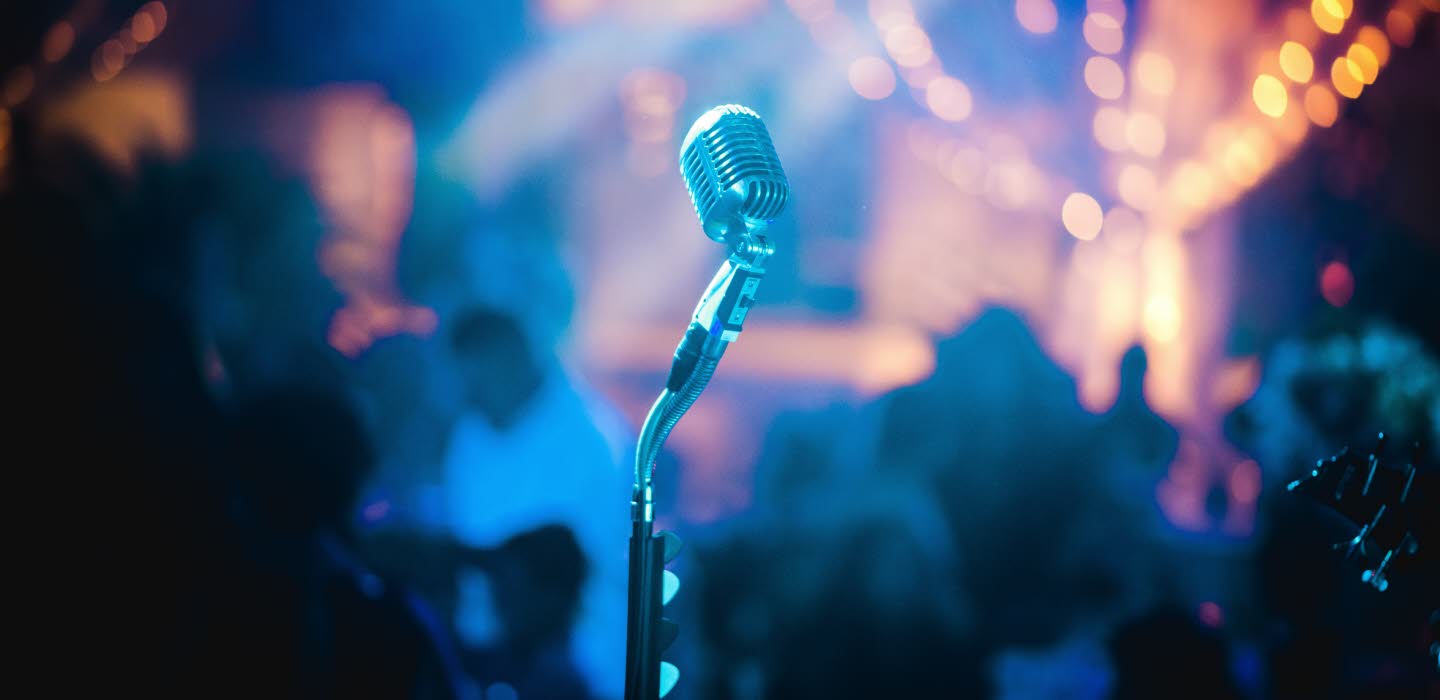 Närbild på mikrofon mot ett publikhav.