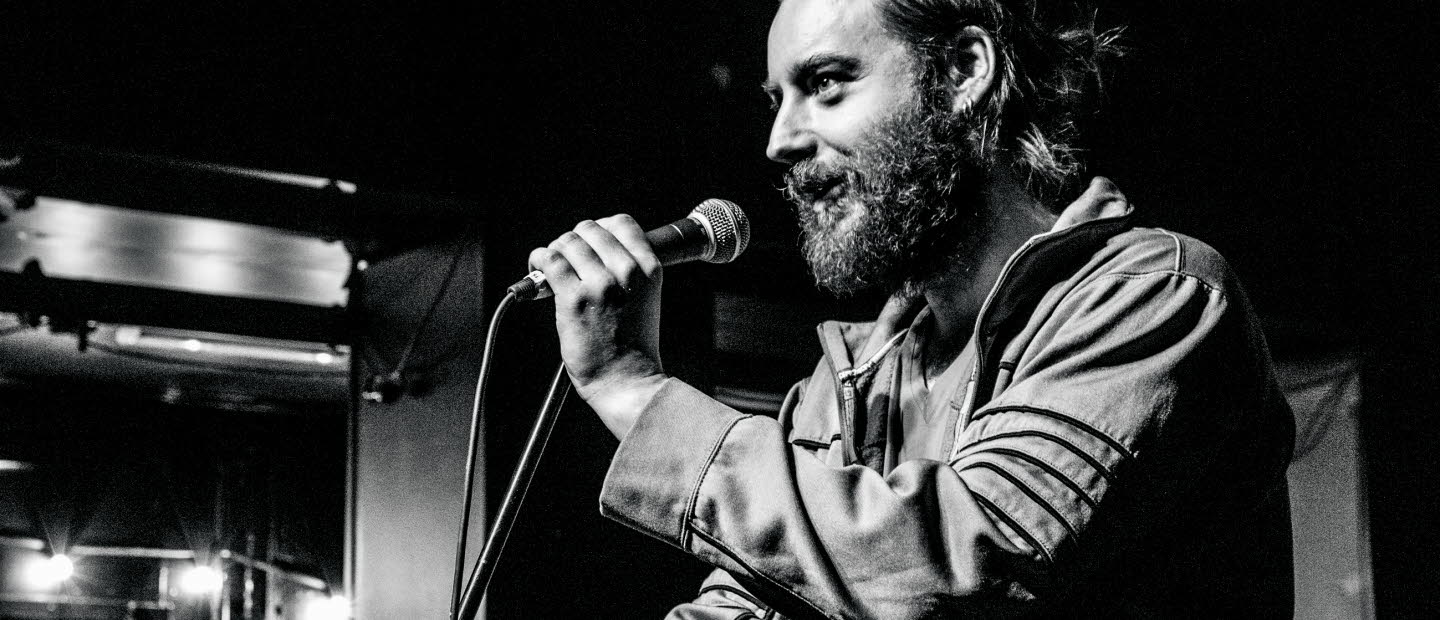 Photo of christian on stage talking into a microphone.