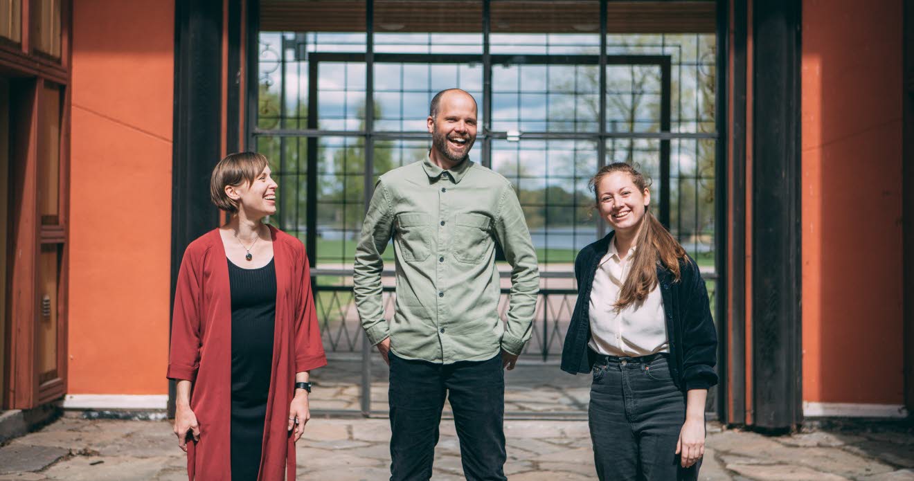 Sara Jane, Olof Göthlin och Tove Klang från Scenbruket står framför byggnaden. Det är sommar och de ser glada ut.