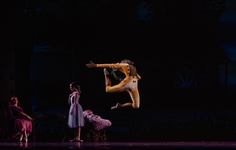 Uppträdande på scen med dansare. En man i orangea kläder kastar sig upp i luften.