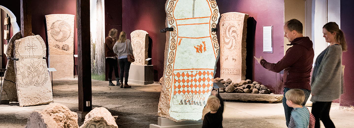 Familj tittar på gotländska bildstenar på Gotlands museum.