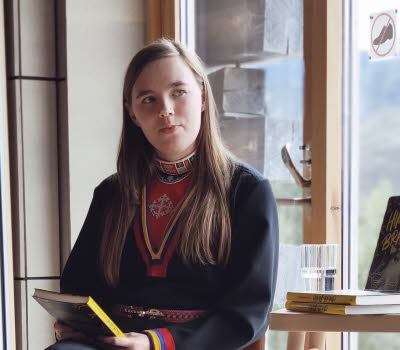 Kvinna samtalar vid fönster.