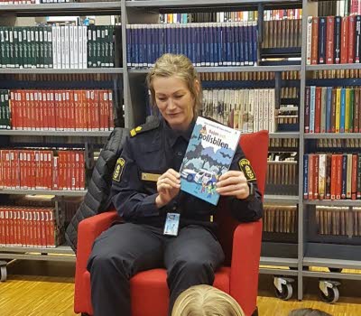 Lokalpolis läser för barn på Hagfors bibliotek.