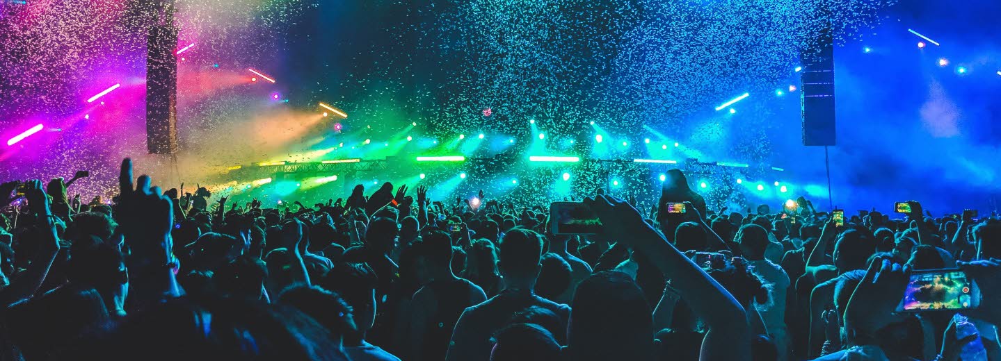 Publikhav framför konsertscen med färgsprakande landskap som scenografi.