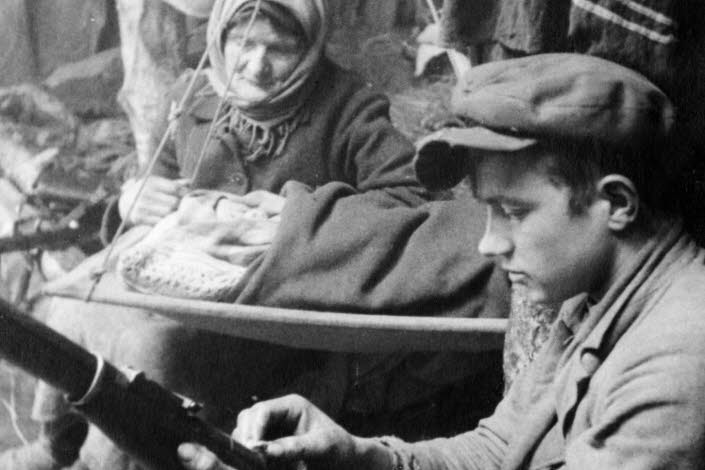 Book cover of "onda nätters drömmar", an old photo of a young man loading a gun, and old woman is looking at him.