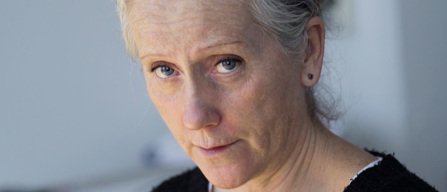 Portrait of Eva Lindström. She's wearing a black sweater and is looking towards the camera, holding a pencil.