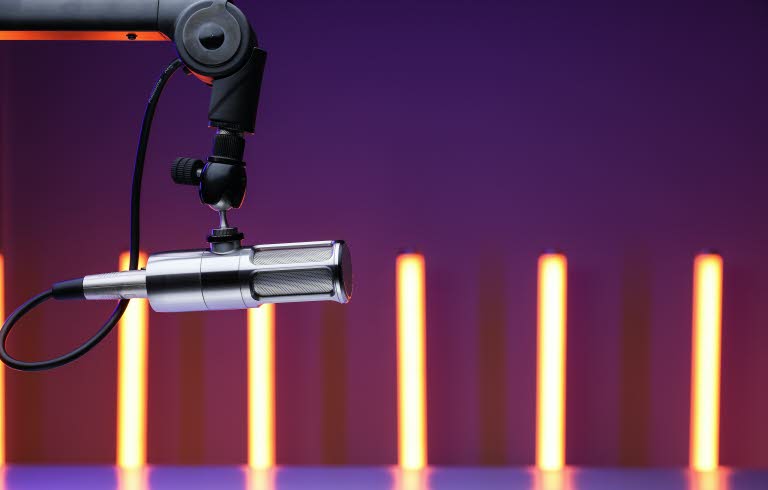 Foto på mikrofon. Smala ljuspelare i bakgrunden.